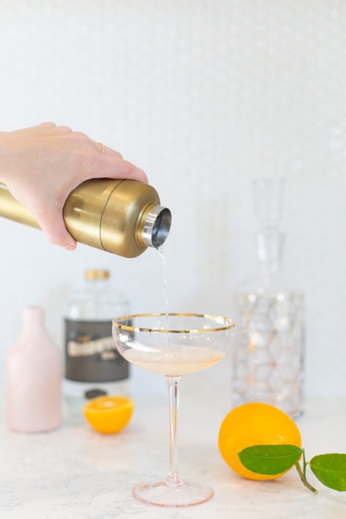 hand pouring cocktail into a glass