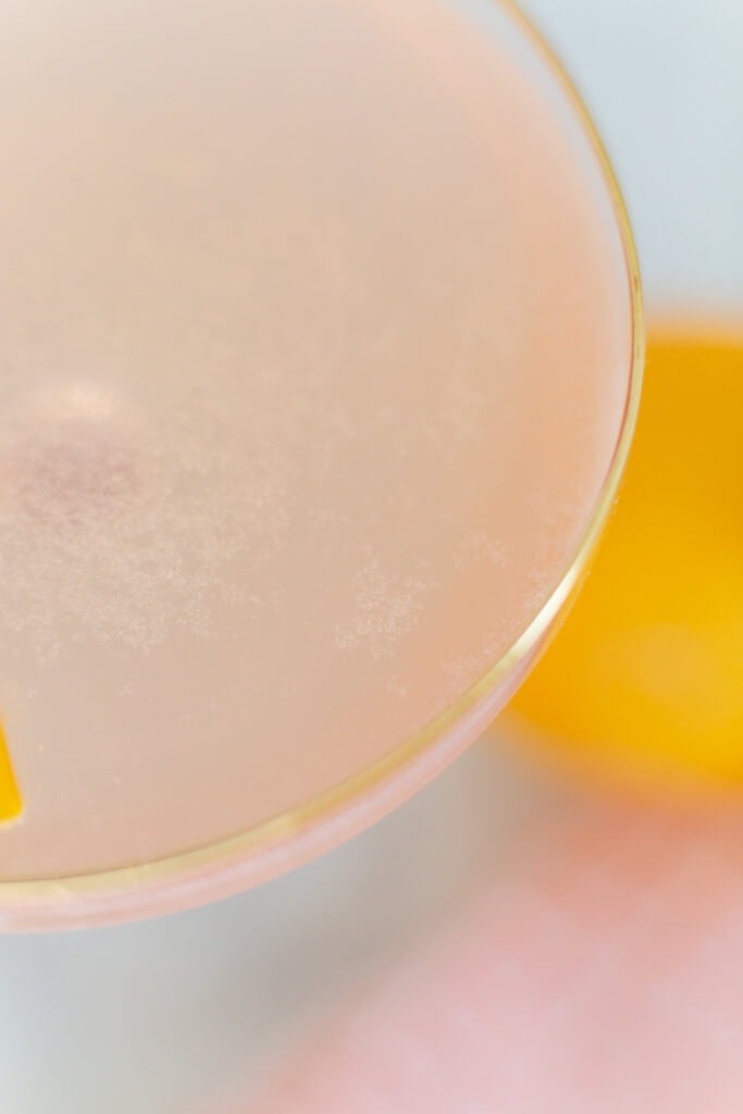 close up of pink cocktail in a gold-rimmed glass