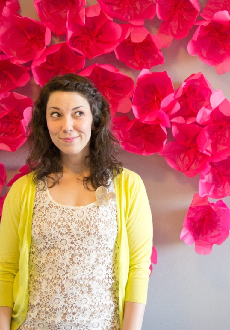 woman standing in front of a paper flower wall
